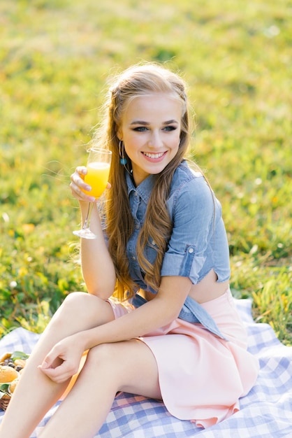 Photo jolie fille joyeuse assise sur une couverture et passant le week-end à se détendre dans le parc à l'extérieur