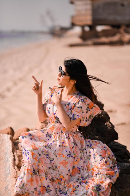 jolie fille joyeuse décontractée se détendant et pointant de côté sur le modèle pakistanais indien de la plage