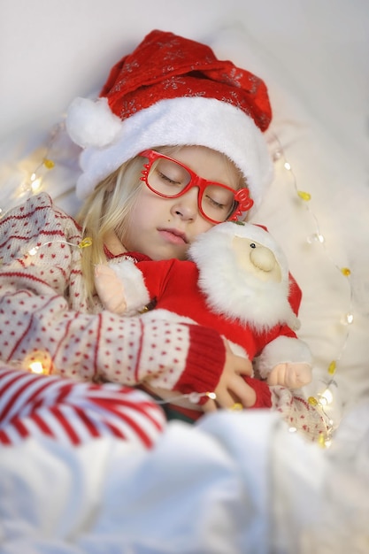 Une jolie fille à lunettes dormant avec un jouet de noël et attendant un miracle sur fond blanc