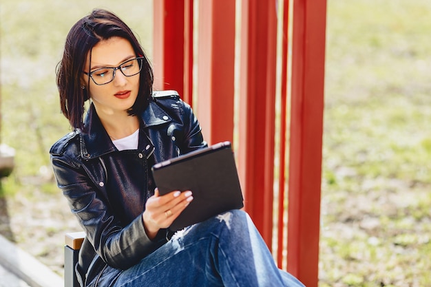 Jolie fille à lunettes avec tablette au parc