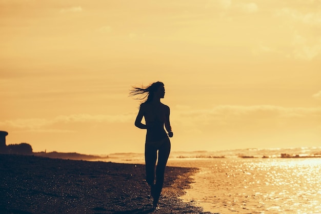 Jolie fille en maillot de bain jaune s'exécutant sur la plage de sable