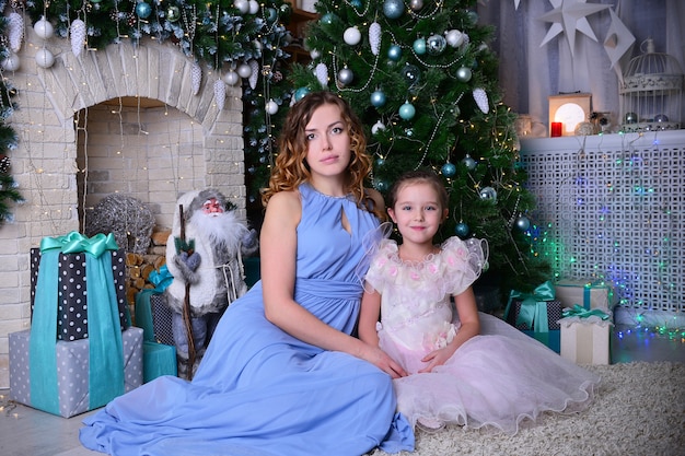 La jolie fille avec maman décore un sapin de Noël dans la maison