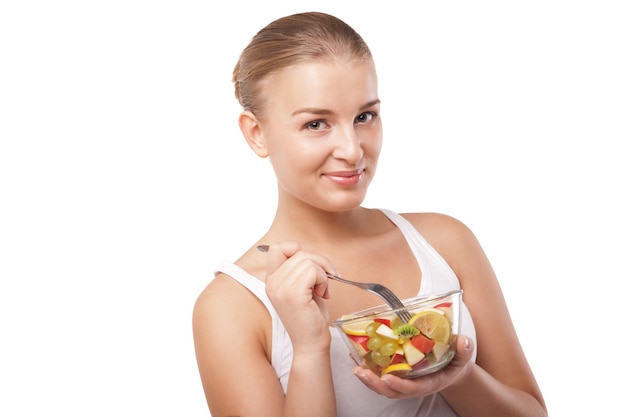 Jolie fille mangeant une salade de fruits isolée