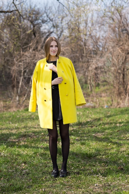 Jolie fille en manteau jaune à l'extérieur