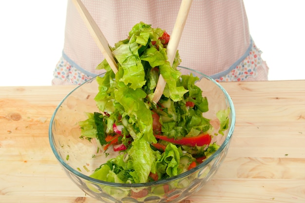 Jolie fille mélanger une salade .Studio, fond blanc. Salade végétarienne saine