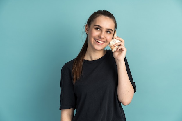 Jolie fille met la coquille à son oreille écoute