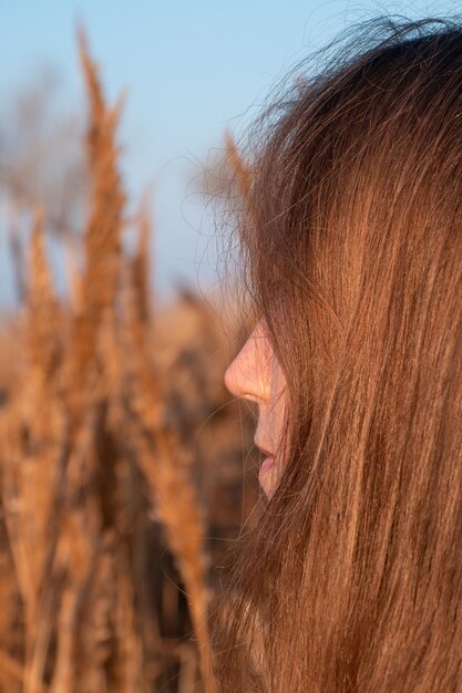 Jolie fille millénaire avec de longs cheveux blonds sur fond d'herbe de pampa roseau sec