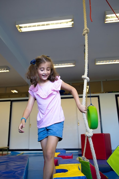 Jolie fille avec des nattes jouant avec les cordes dans le gymnase de son école.