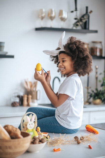 Jolie fille avec des oreilles de lapin dans la cuisine souriant joyeusement