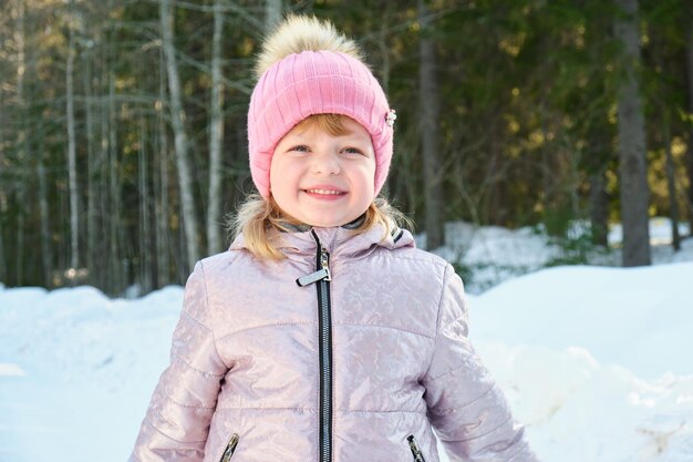 Jolie fille par une journée d'hiver ensoleillée sur fond de neige et de forêt