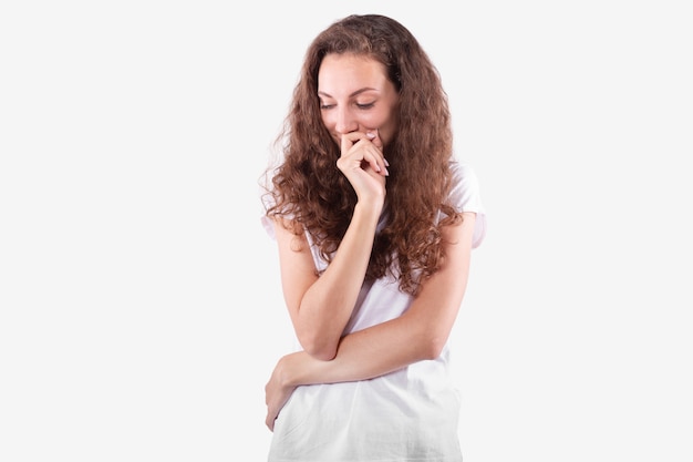 Jolie fille pose timidement de manière ludique pour une séance photo. Fond blanc isolé