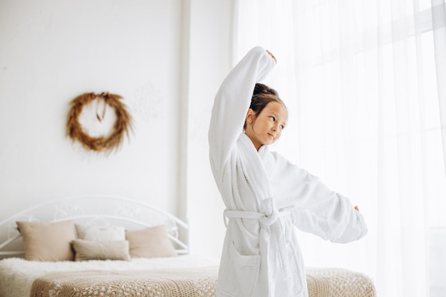 Jolie fille préadolescente sur le lit portant un peignoir