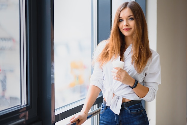 Jolie fille prenant un café près de la fenêtre