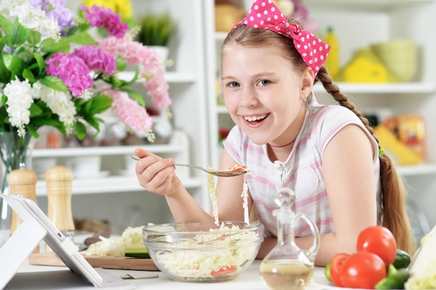 Jolie fille préparant une délicieuse salade fraîche dans la cuisine