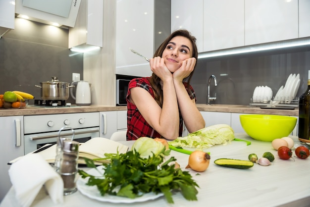Jolie fille prépare une salade de différents légumes et légumes verts pour un mode de vie sain