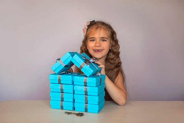 Jolie fille près de coffrets cadeaux bleus formés comme une maison