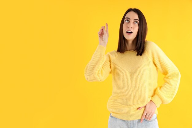 Jolie fille en pull sur fond jaune