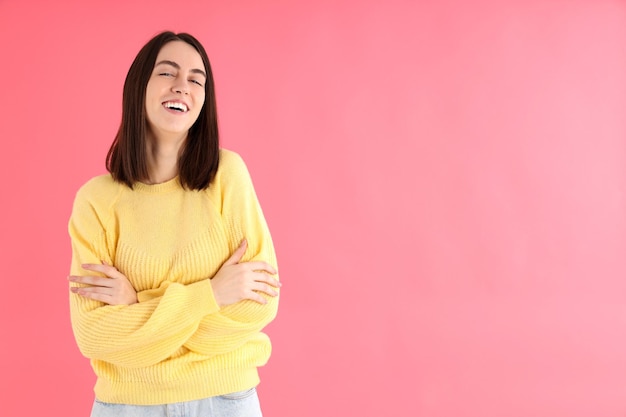 Jolie fille en pull jaune sur fond rose