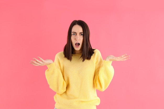 Jolie fille en pull jaune sur fond rose