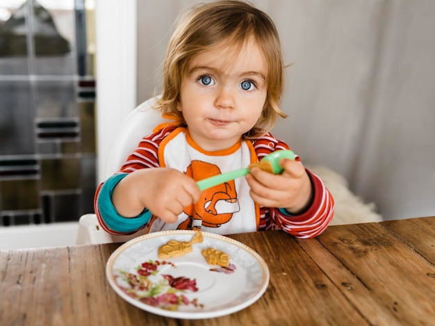 Photo une jolie fille qui déjeune assise à la maison.