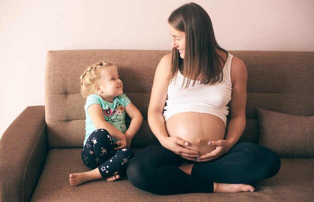 Jolie fille regardant la mère enceinte souriante et riant