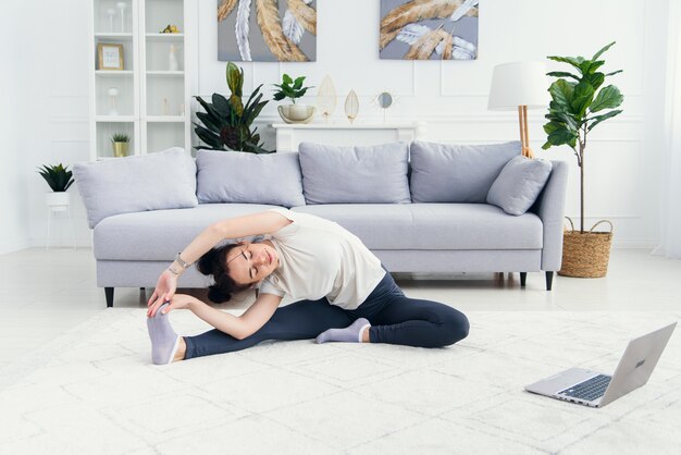 Photo jolie fille regardant le tutoriel de yoga sur ordinateur portable