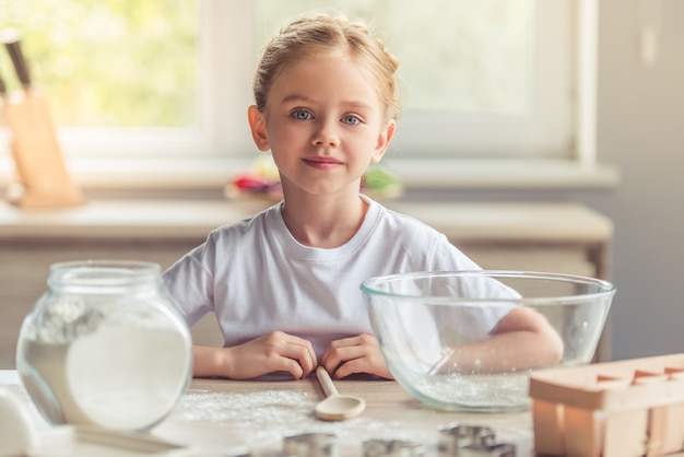 Jolie fille regarde la caméra et sourit pendant la cuisson