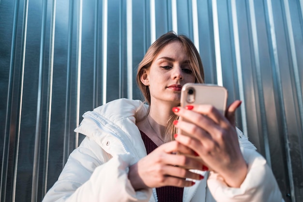 Une jolie fille regarde dans un smartphone et prend un selfie de haute qualité