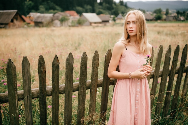 Jolie fille en robe rose près d'une clôture