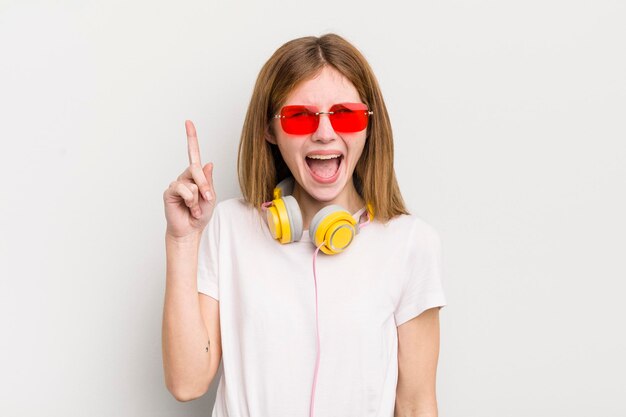 Jolie fille rousse se sentant comme un génie heureux et excité après avoir réalisé une idée écouter le concept de musique