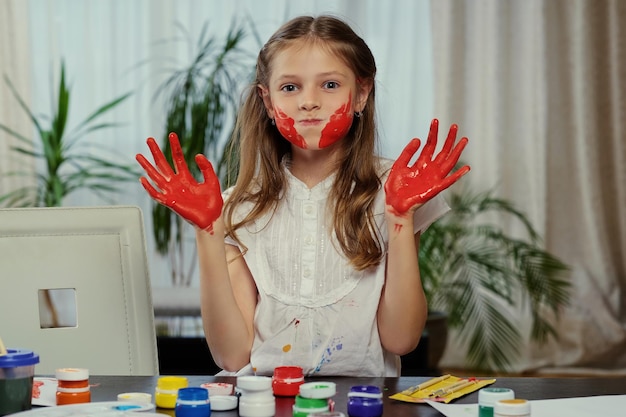 Jolie fille s'amusant et montrant des mains peintes.