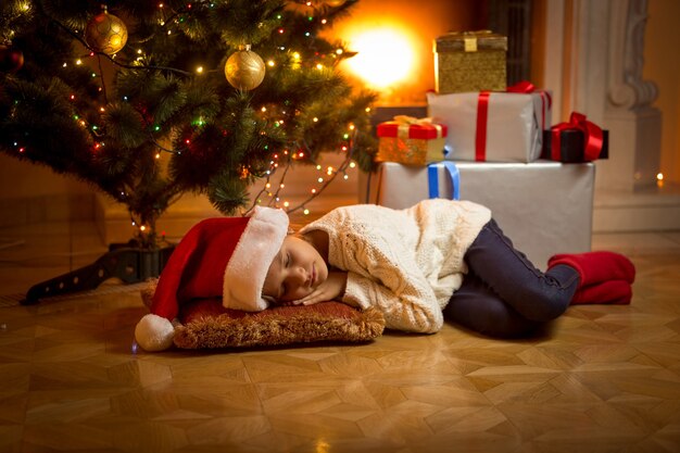 Jolie fille s'est endormie sous le sapin de Noël en attendant le Père Noël