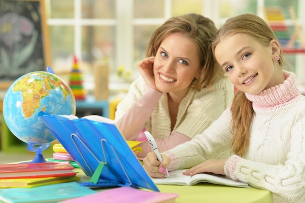 Jolie fille avec sa mère faisant ses devoirs ensemble