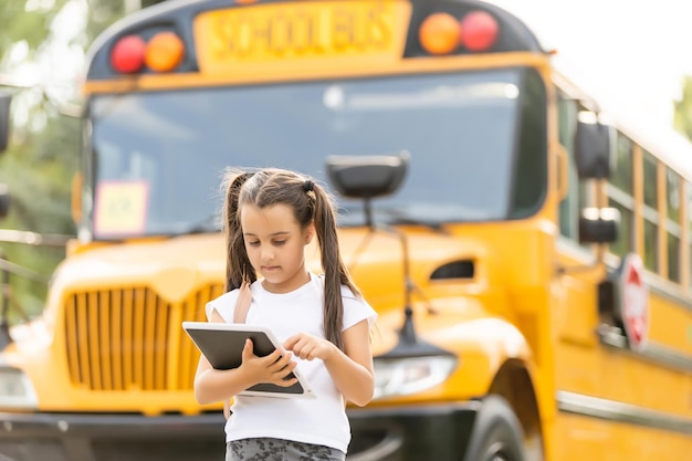 Photo jolie fille avec un sac à dos debout près du bus allant à l'école posant devant la caméra pensive close-up