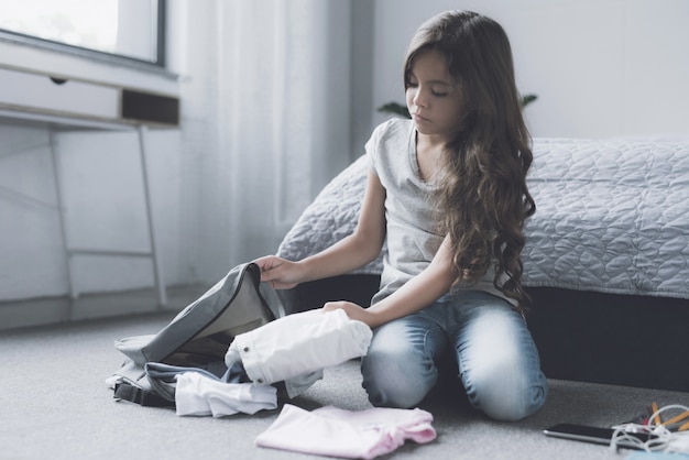 Jolie fille, sac de rangement, assis par terre dans la chambre