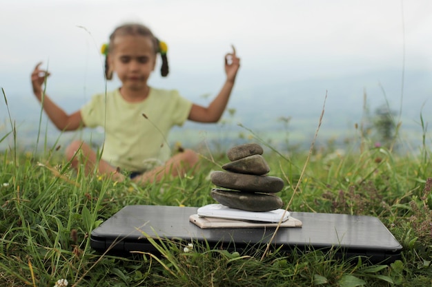 Photo une jolie fille se détend dans les montagnes une pile de pierres zen et de gadgets numériques ordinateur portable et téléphones portables