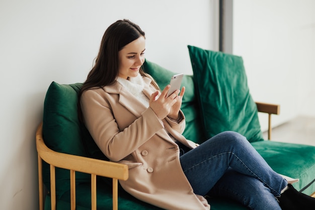 Jolie fille se détendre et utiliser le téléphone sur le canapé dans le centre commercial.