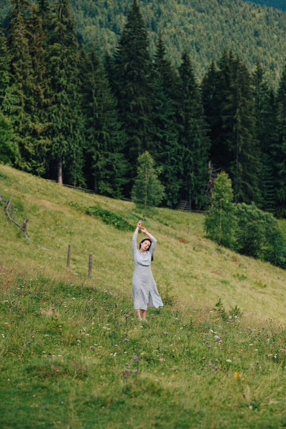 Jolie fille se tient dans les montagnes et aime la nature