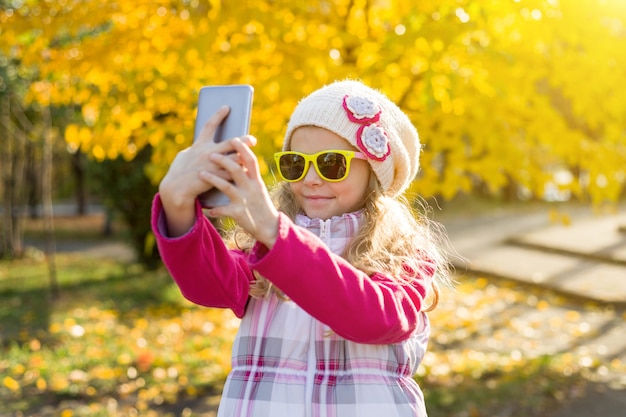 Jolie fille de sept ans faisant selfie à l'aide de smartphone