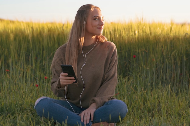 Jolie fille avec son mobile, écouter de la musique dans la nature