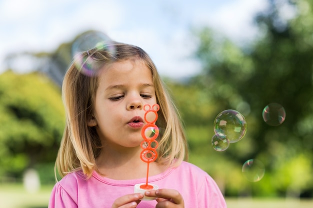 Jolie fille soufflant des bulles de savon au parc