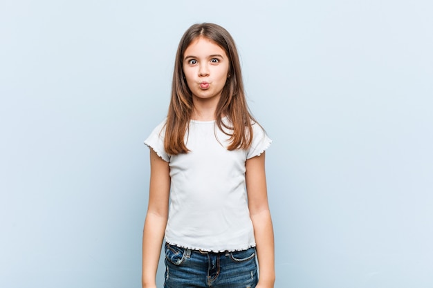 Jolie fille souffle les joues, a une expression fatiguée