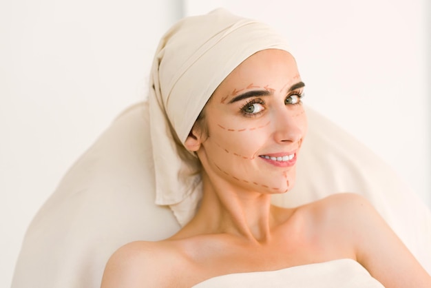 Jolie fille avec des sourcils noirs et des épaules nues sur fond blanc et regardant la caméra. Sourire de femme.