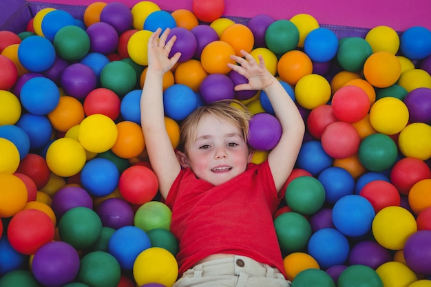 Jolie fille souriante dans la piscine à balles éponge