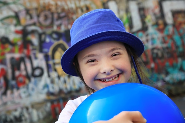 Jolie fille souriante du syndrome de Down sur le fond du mur de graffitis