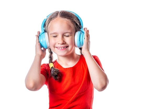 Jolie fille souriante européenne écoutant de la musique avec un casque sans fil isolé sur fond blanc.