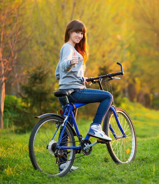 Jolie fille souriante, faire du vélo dans le parc