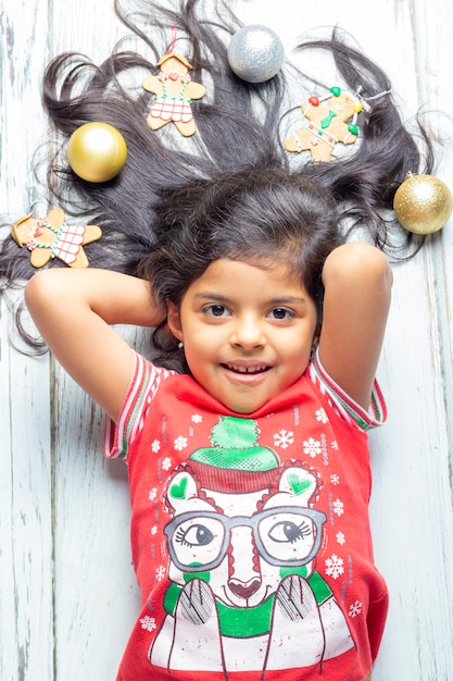 Jolie fille souriante joyeuse avec des cheveux de Noël décorés