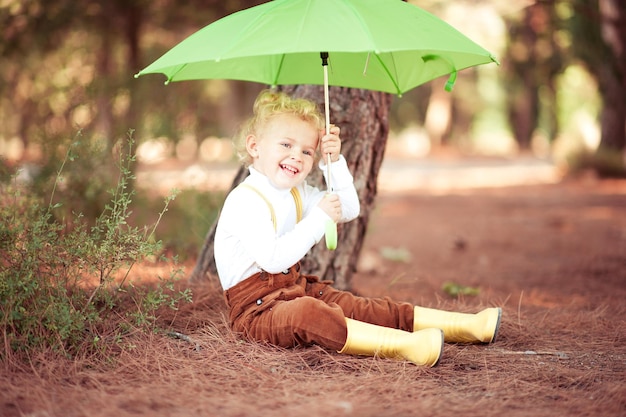 Jolie fille souriante tenant un parapluie s'amusant dans le parc d'automne en plein air