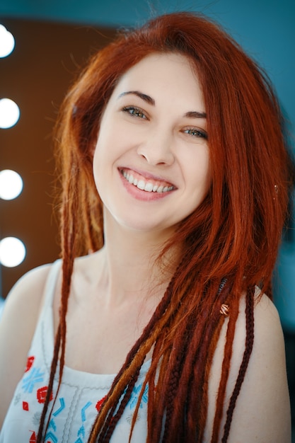 Jolie fille sourit et regarde le portrait de la caméra d'une femme rousse avec des dreadlocks dans un salon de beauté u...